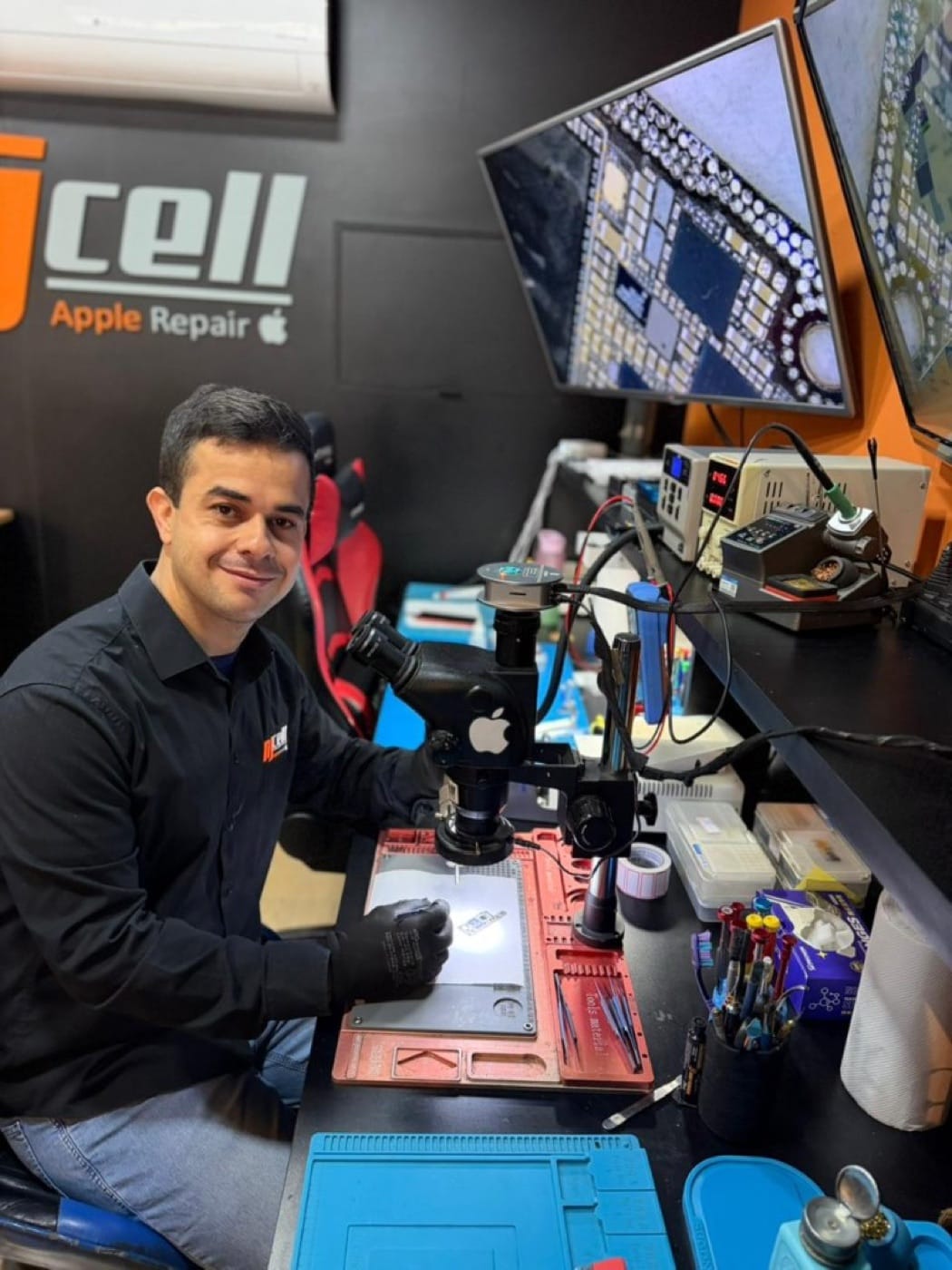 Técnico NJCELL - assistência Apple em Sorocaba Técnico da NJCELL em laboratório com microscópio para reparo de iPhone em Sorocaba